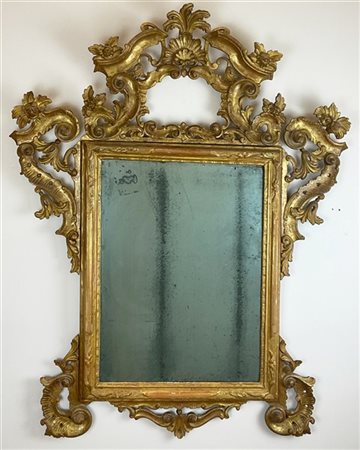 Specchiera in legno intagliato e dorato con cimasa e fregi traforati a volute c