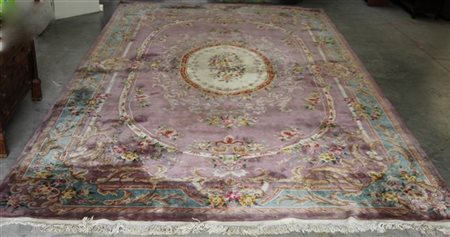 Grande tappeto Cina fondo vinaccia decorato a motivi floreali policromi, volute