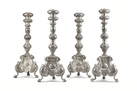 Gruppo di quattro candelieri in argento con fusto tornito e decorato a fiocchi,