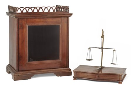 Bilancia per orafo entro vetrina in legno con anta a vetro, sormontata da corni