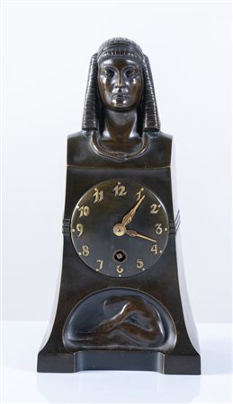 BAGDONS. Scultura simbolista in bronzo con orologio con numeri arabi, sormontato da testa di sfinge con al collo serpente che si morde la coda e alla base giovane donna distesa. Al retro firma T. Bagdons, 1902. Cm 26.5x13x8.