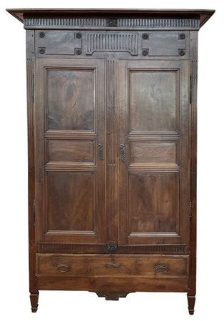 Armadio in noce a due ante con cassetto alla base, decorato da scanalature e fi