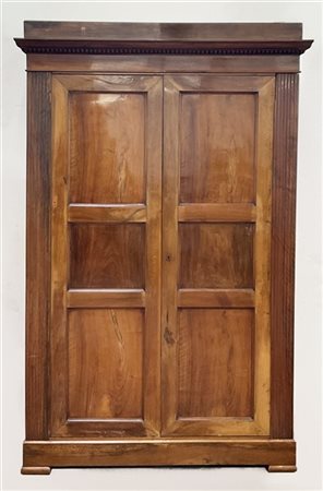 Armadio in noce a due ante pannellate fra lesene scanalate, ripiani interni. Se