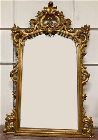 Specchiera in legno intagliato, traforato e dorato con cimasa decorata a volute