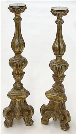 Coppia di candelieri in legno intagliato e dorato a mecca con base tripode a vo