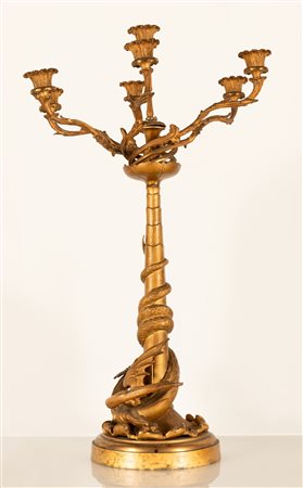 Grande candelabro a 7 fuochi in bronzo dorato. Figura di drago alato alla base con coda attorcigliata al fusto.   