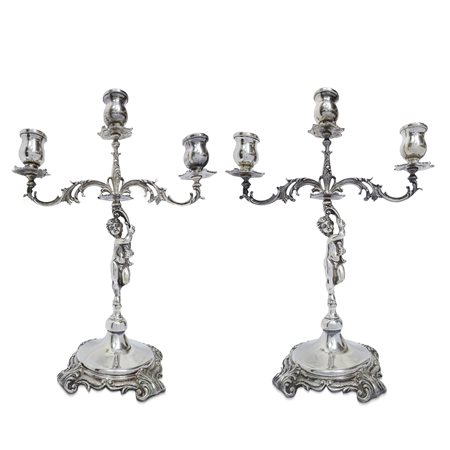 Coppia di candelabri in argento a tre luci con putti a sostegno 
