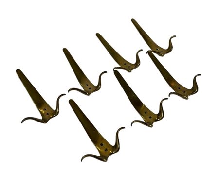 Gruppo di sette appendiabiti in ottone di forma mossa. Italia, anni '50/'60. (h