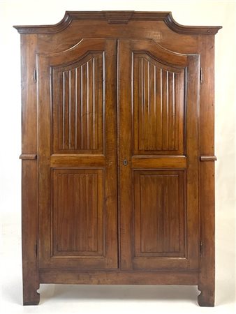 Armadio in noce a due ante sagomate e scanalate, cappello mosso. Secolo XIX (cm