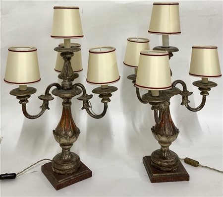 Coppia di lampade a quattro fiamme in legno intagliato e argentato, bracci a vo