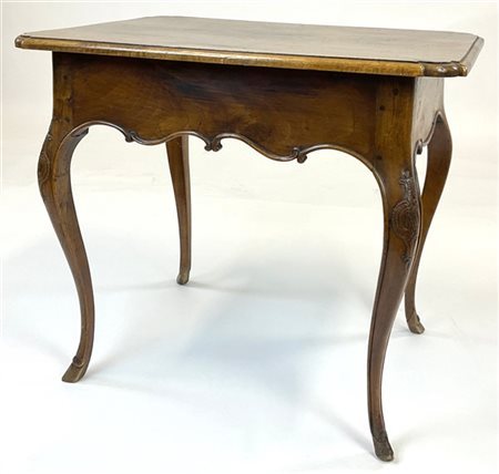 Tavolino in noce con piano sagomato, gambe mosse terminanti a zoccolo ed intagl