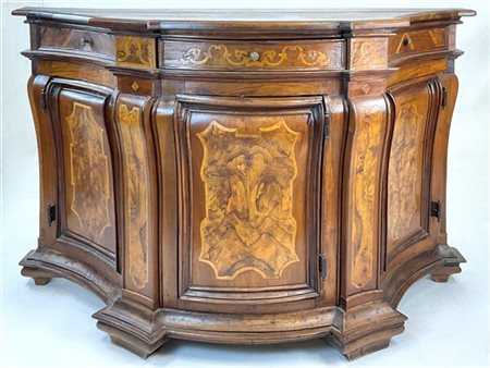 Antica credenza in legni vari, di forma mossa a tre ante e un cassetto sottopia