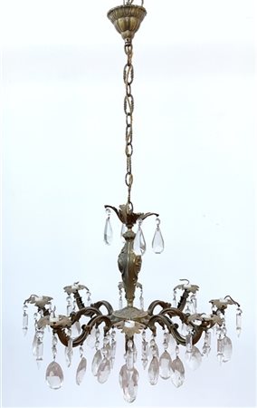 Lampadario in metallo decorato in rilievo a otto luci. Bracci sagomati e penden