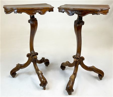 Coppia di guéridon in noce intagliato con piano sagomato e bordato da volute, s