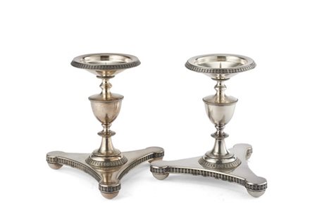 Coppia di candelieri in argento con fusto tornito e base tripode, profili cesel