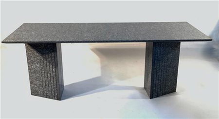 Tavolo in granito con piano ad angoli arrotondati e sostegni triangolari. Itali