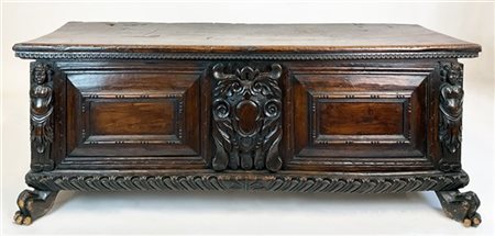 Cassapanca in noce intagliato e scolpito con coperchio a profilo dentellato, su