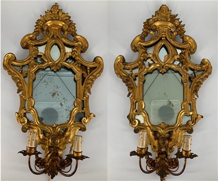 Coppia di ventole a due luci in legno intagliato e dorato con decoro a volute,