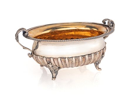 Centrotavola biansato di forma ovale in parte baccellato piedi con attacco a...