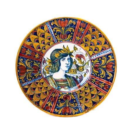 Piatto in maiolica decorato a lustro metallico. Nella tesa si alternano decori a penna di pavone con altri a fiori fantastici. Nel cavetto figura muliebre e cartiglio " Fiorella"