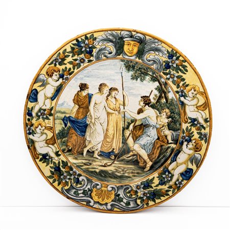 Grande piatto istoriato con tesa decorata con putti, serti fioriti, mascherone e cartigli. Al cavo con scena dal Giudizio di Paride   Fedele Cappelletti (attribuito a)