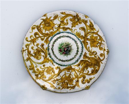 Piatto in stile robbiano con baccanale sulla tesa e cavetto. Al retro grottesche e al centro fiori in doppia ghirlanda   Manifattura toscana del XIX secolo