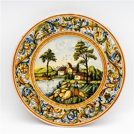 Piatto raffigurante girali nella tesa e pastorella con gregge in paesaggio fluviale. Manifattura Rapino   