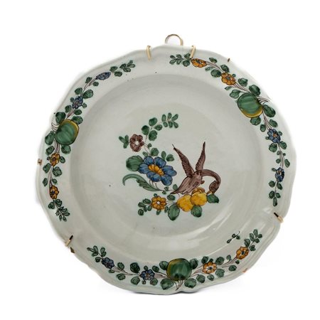 Piatto in maiolica con bordo mistilineo decorato alla tesa con tre composizioni di fiori e frutti  Manifattura di Cerreto Sannita della fine del XVIII secolo