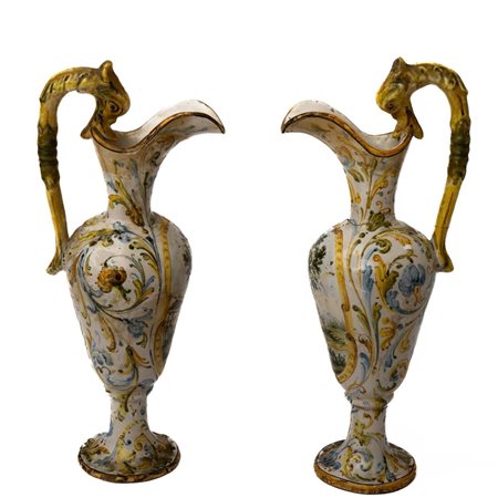 Coppia di piccoli versatoi in maiolica con decoro a girali fogliati e con paesaggi nelle riserve, anse a foggia di animale fantastico   Manifattura del Centro Italia della fine del XIX secolo