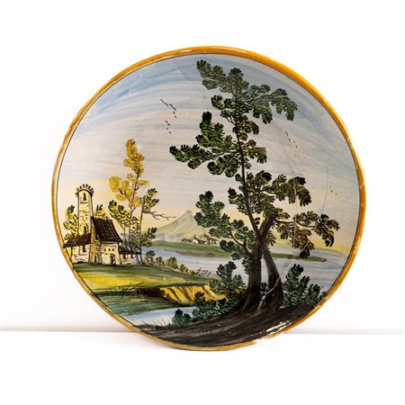 Piatto in maiolica con paesaggio fluviale, torre, case e albero    Manifattura di Castelli della metà del XX secolo