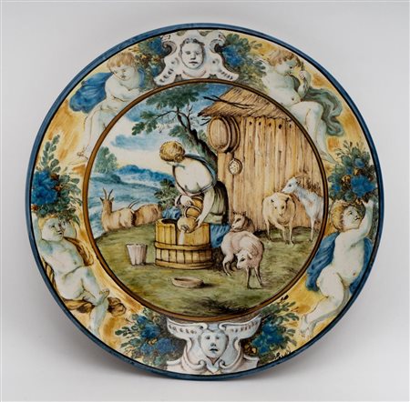 Piattino con scena pastorale nel cavetto e putti, cartigli e serti fioriti nella tesa   Manifattura di Castelli della fine del XX secolo