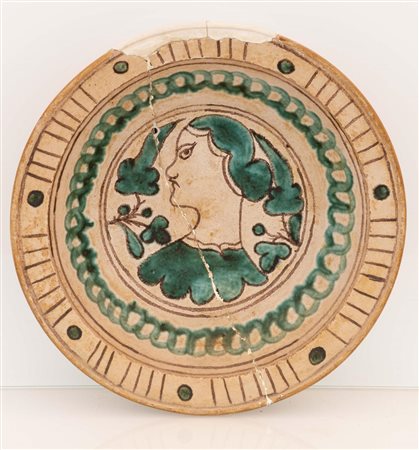 Piatto in ceramica ingobbiata graffita ed invetriata con motivi decorativi in verde ramina ad archetti e geometrici nella tesa e nel cavo ritratto di una "bella" posta di profilo con motivi vegetali. 