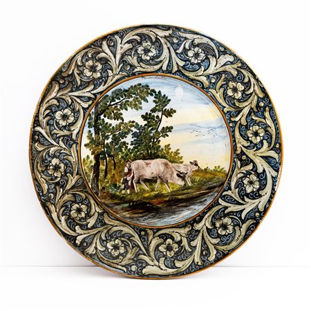 Grande piatto con decoro a girali fogliati sulla tesa e nel cavetto donne e bambino con armenti che si abbeverano al greto del fiume   Manifattura di Castelli della metà del XX secolo