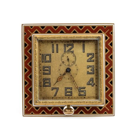  Luga: Orologio sveglia da tavolo Art Déco  in metallo dorato e smalti policromi. Svizzera, anni '20 - '30