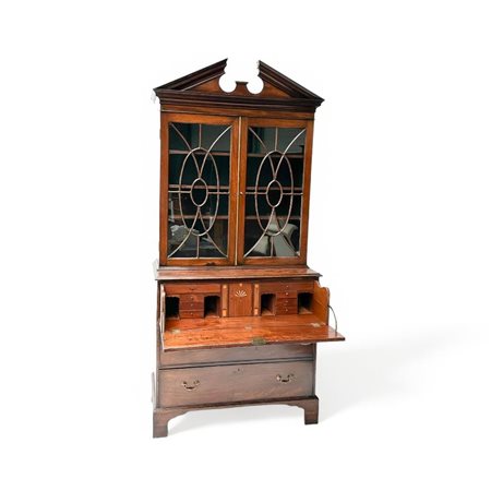 An English mahogany secretary with a raised edge on which a broken frieze....