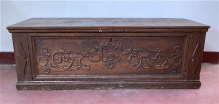 Antica cassapanca in legni vari con fronte decorato da intagli a grifoni e volu