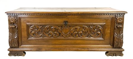 Cassapanca in noce con fronte centrato da pannellatura intagliata a volute e sc