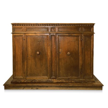 Grande credenza bassa in legno di noce, piano a becco di civetta sottolineato da  dentellatura intagliata, due ante con gangheri cornice alla base, fine 18° secolo