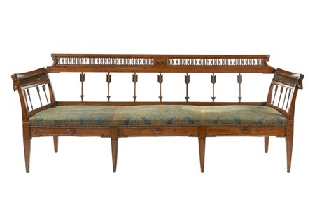 Divano in noce intagliato, schienale a giorno con elementi in forma di freccia.