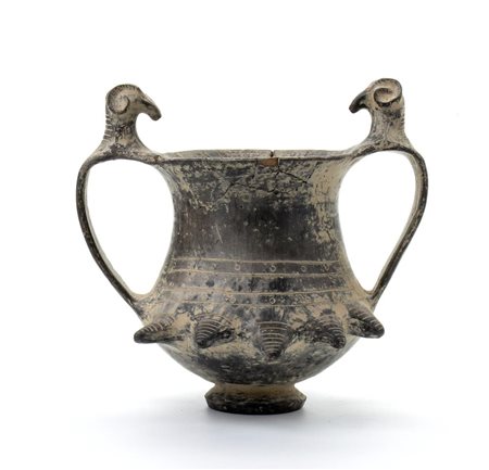 Coppa biansata in ceramica buccheroide con decori a rilievo di testa di montone sulle anse e umbonati sul corpo   