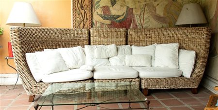 Grande divano con struttura in legno e rattan a tre moduli. Schienale curvo.   