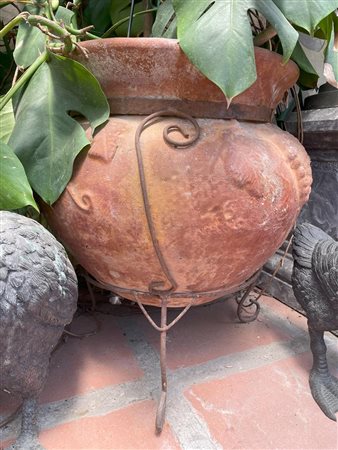 Vaso in terracotta con tralci di vite a rilievo su tripode in ferro lavorato a volute   