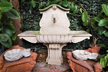 Fontana in marmo bianco a vasca unica arricchita da volute laterali e conchiglia centrale.   