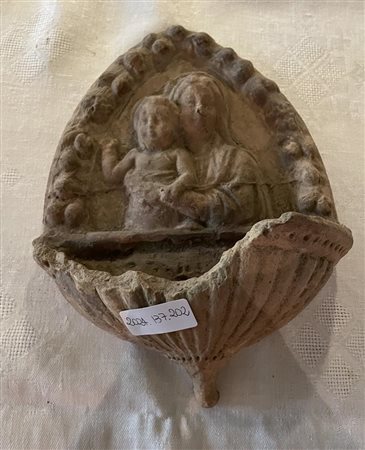 Frammento di acquasantiera raffigurante la Madonna con in braccio il Bambino in un serto ogivale di fiori.    
