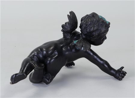A dark patinated bronze putto. 20th century.14 x 23 cm.