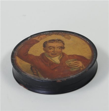 A paper mache snuffbox, with a man with a feather and a drinking glass on the...
