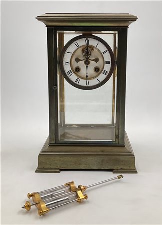 Pendola d'appoggio con cassa in vetro e ottone. 
Quadrante a fascia in smalto b