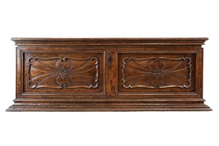 Cassapanca in noce con fronte decorato da doppia pannellatura intagliata a ragn