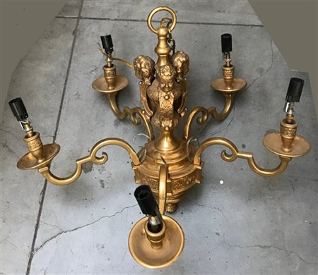 Lampadario in bronzo dorato a cinque fiamme con sostegno decorato da teste di f