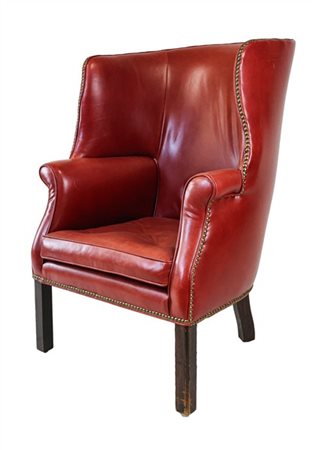 Poltrona a orecchioni di forma sagomata rivestita in pelle rossa borchiata. Ing